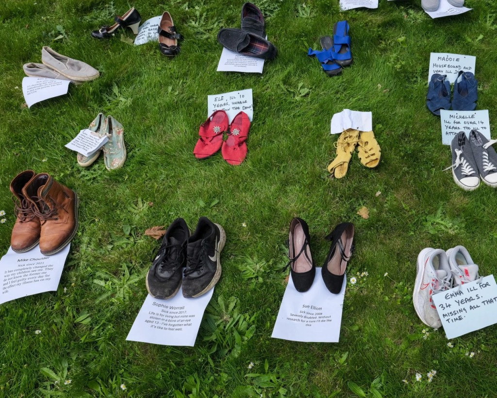 Shoes on grass with name tags and 'years been ill' on them along with demands for funding